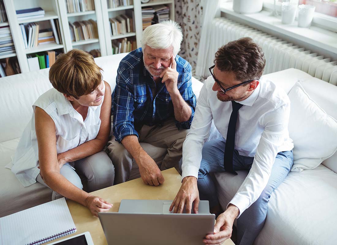 Flexible Spending Account - Senior Couple Planning Their Investments with a Financial Advisor from the Comfort of Their Home While Sitting on the Sofa of Their Living Room