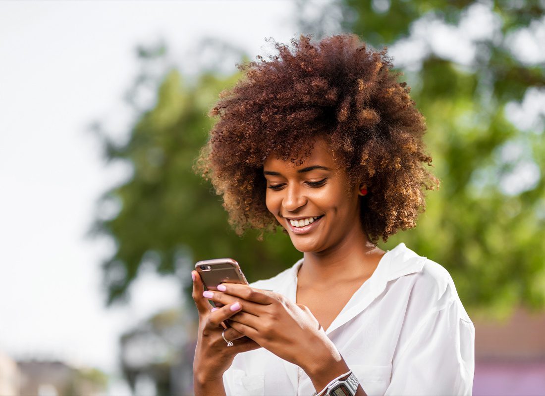 Read Our Reviews - A Young Woman Smiling Happily at Her Phone